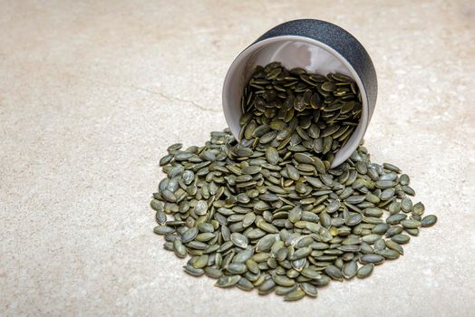 Pumpkin seeds. Peeled pumpkin seeds are in a black saucer. On a black cutting board made of stone.