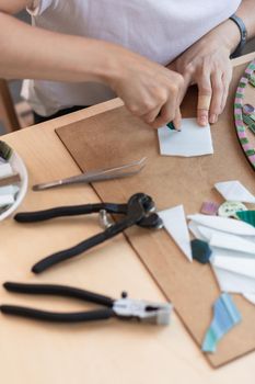 Workplace of the mosaic master: women's hands holding tool for mosaic details in the process of making a mosaic. Close-up. Creative process. Masterclass handmade