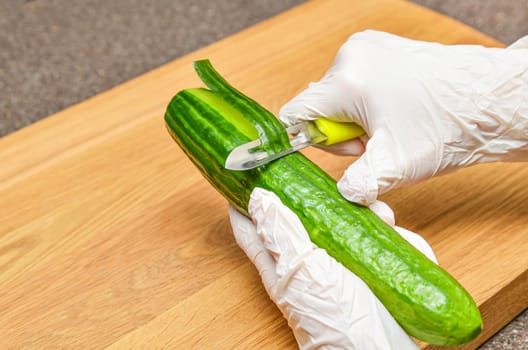 peeling cucumber, woman in rubber gloves peeling cucumber peel, healthy lifestyle and diet concept
