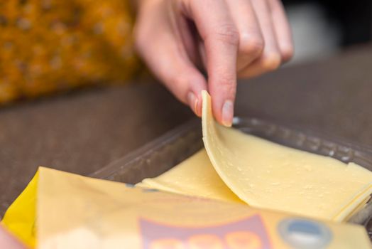 Opens a bag of sliced cheese, a woman opens a bag of cheese, pieces of cheese in a bag.