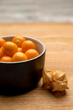 Physalis fruits on a wooden table. Sweet yellow physalis berries in a cup on wood background.