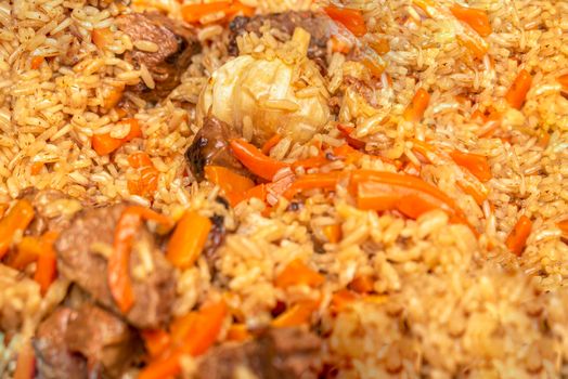Pilaf close-up. Oriental cuisine concept. National Uzbek pilaf with meat in a cast-iron pan. Top view, lamb, devzira rice,garlic.