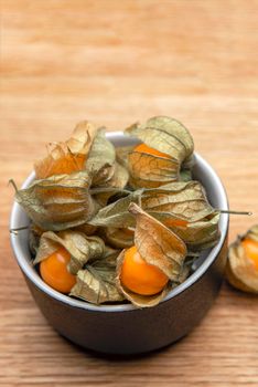 Physalis fruits on a wooden table. Sweet yellow physalis berries in a cup on wood background.