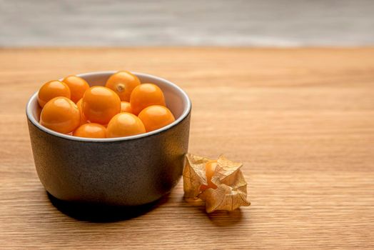 Physalis fruits on a wooden table. Sweet yellow physalis berries in a cup on wood background.