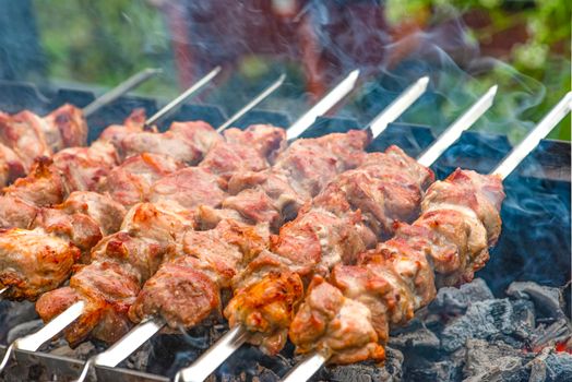 Grilled pork meat on metal skewers. Barbecue cooking. The smoke from the coals develops over the meat. Promotional banner for menu with copy space to insert text.