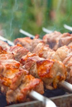 Cooking barbecue, grilled meat barbecue. Cooking pork shashlik on metal skewers. Smoke from embers builds up over the dish. Advertising banner with copy space.