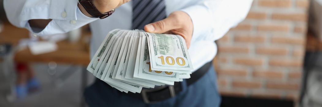 Close-up of male hands show ok sign with bunch of banknotes, businessman with big loan, monthly salary, money for investment. Finance, wealth, success, financial progress, banking concept