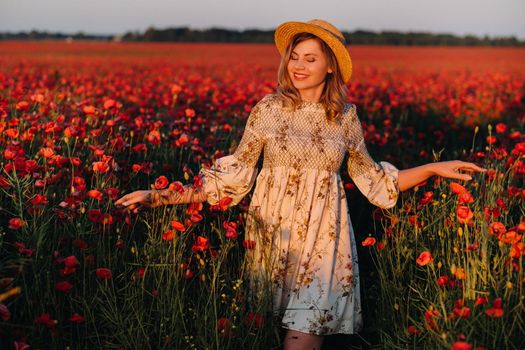 a girl in a dress, in a hat walks in a field with poppies at sunset.