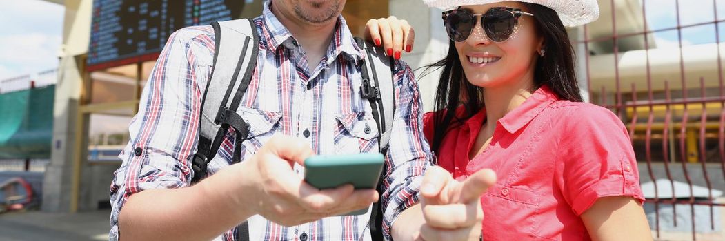 Portrait of smiling woman and man trying to find way via map application on smartphone. Point with finger in right direction, way to place. Navigation, gps, travel, location, route concept