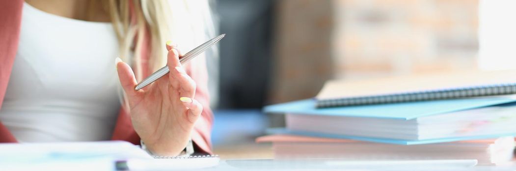 Close-up of female busy with papers on desk, accumulated documents and problem projects, day in rush. Clever company worker in private office. Business, career, success concept. Blurred background