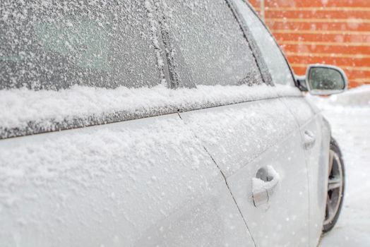 Frozen rearview mirror, snowy car. Winter snow snowfall.