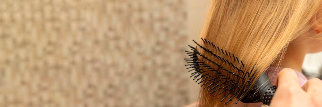 The girl combs her hair with a comb in the bathroom. Place for your text. Home hair care concept
