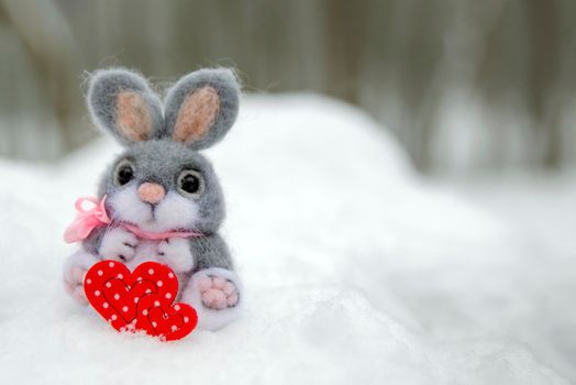 Happy Valentine's Day greeting card or banner. Plush rabbit holding a red heart ka symbol of love. Holidays Happy Valentine's Day