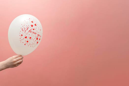 Valentine's card with place for text. Balloon with the inscription love in the child's hand. On a pink background.
