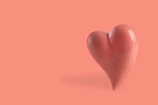 Pink heart on a pink background float in the air, casting a shadow. Valentine's day concept