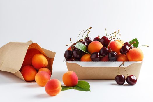 Apricots and cherries in paper packaging on a white background. the concept of eco-friendly packaging without plastic. copy space