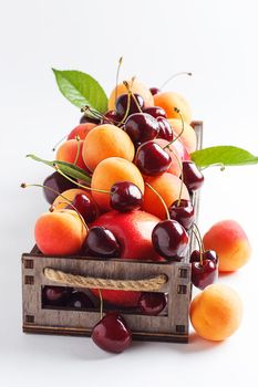 apricots and cherries in a box on a white background