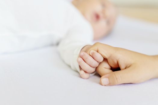 Newborn toddler holds his sister's hand. Selective focus. People.