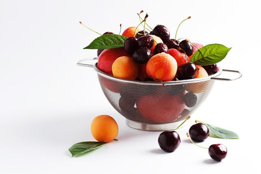 apricots and cherries in a metal bowl on a white background. Copy spase