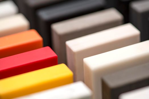 Large selection of stone samples for countertops and floors. Pieces of artificial acrylic stone in a sample box. A set of shades of countertops of different textures.