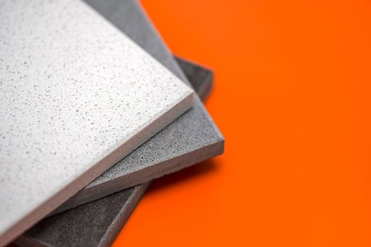 Samples of natural stone for kitchen countertops and floor tiles. Stone samples for countertops on orange background, copy space for design or text.