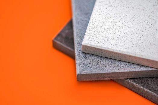 Samples of natural stone for kitchen countertops and floor tiles. Stone samples for countertops on orange background, copy space for design or text.