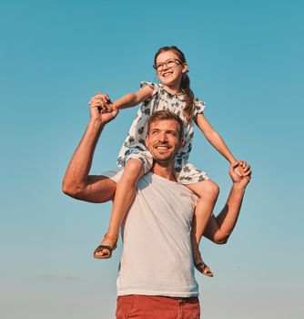 Portrait of a young happy father with his daughter having fun outdoors