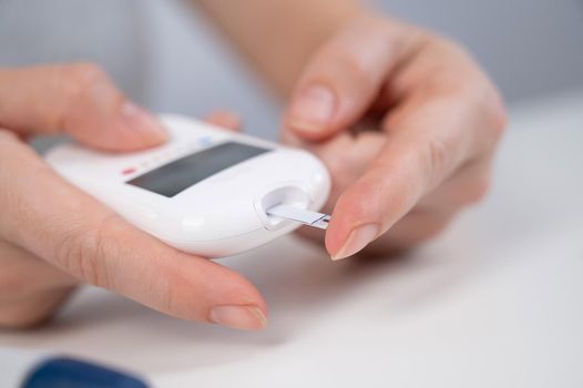 Woman measures blood sugar level with a glucometer