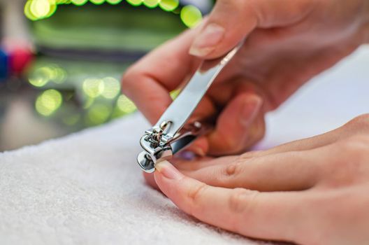 Woman cutting nails with nail clippers - close-up. Home nail care.