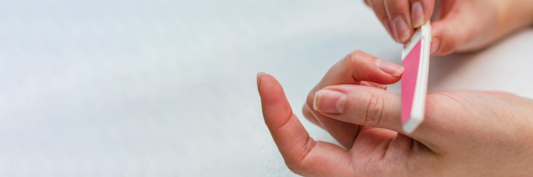 Woman doing manicure with nail file. Home nail care concept.