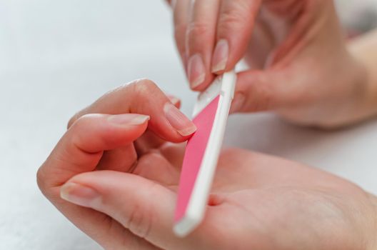 Woman doing manicure with nail file. Home nail care concept.