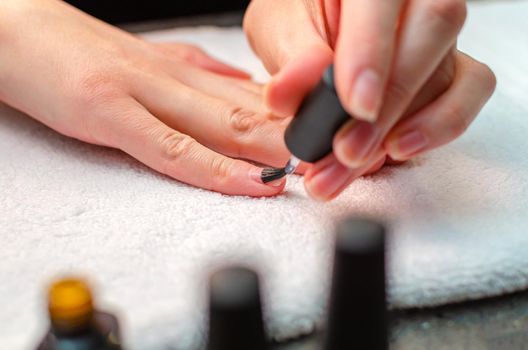 A woman applies a primer to her nails before applying varnish. Close-up of a hand