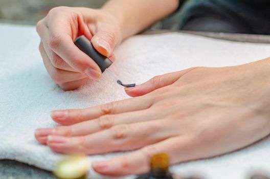 A woman applies a primer to her nails before applying varnish. Close-up of a hand