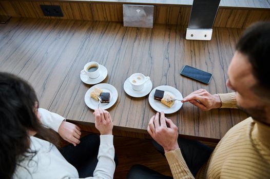 Overhead view of a married couple sitting at wooden table in the restaurant and enjoying delicious breakfast together
