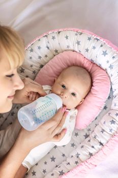 Mother feeds her newborn baby from a bottle. Selective focus. Food.