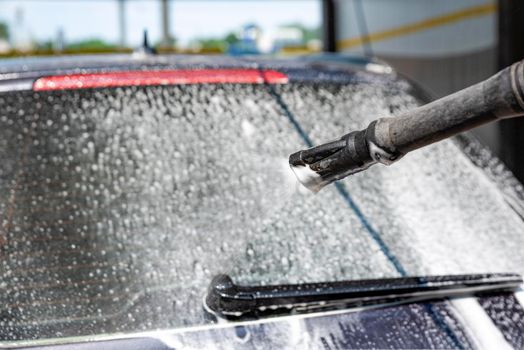 Car wash. The process of washing a car with active foam under pressure. Self-service manual car wash. Car care concept.