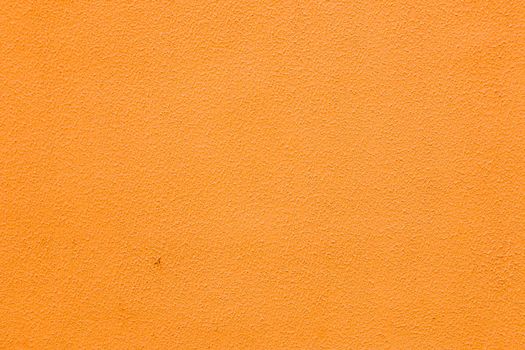 A wall with worn orange plaster.