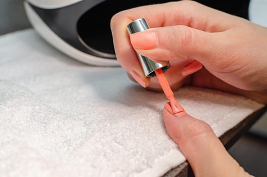 The woman herself does the manicure. Female hands with manicure tools. Nail care concept.