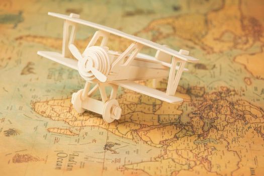 Wooden toy plane on world map on table. Travel and vacation concepts.