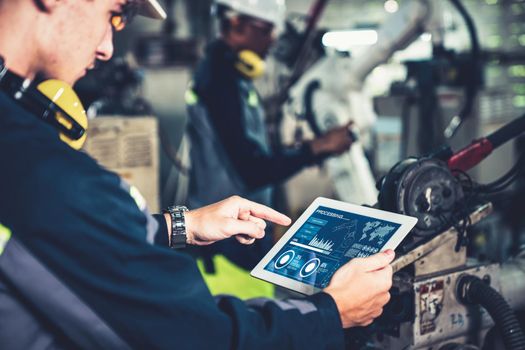 Factory workers working with adept robotic arm in a workshop . Industry robot programming software for automated manufacturing technology .