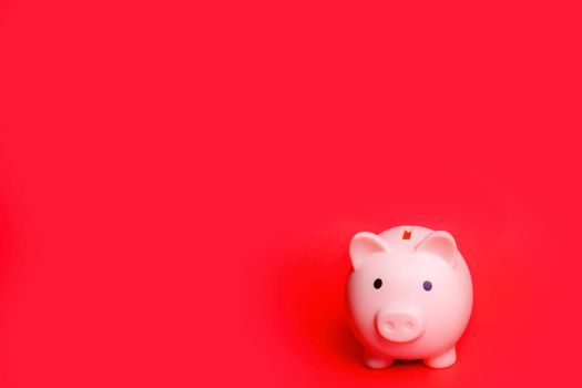 Pink piggy bank isolated against red background