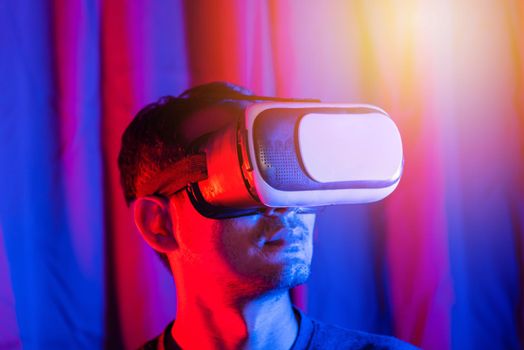 Asian handsome man wear VR helmet excited emotional at home purple and blue background, experiencing virtual reality goggles experiencing reality excited emotional, metaverse and cyberspace