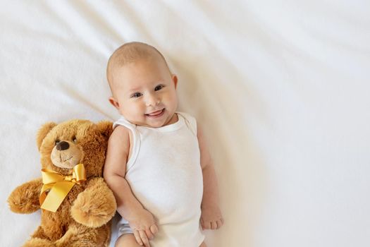 Baby plays with teddy bear against white background. Selective focus. People.