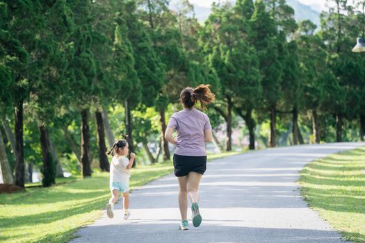 Mother and daughter runners are jogging in the park. Evening. Family activities . Mother and son in sportswear are running and having fun.