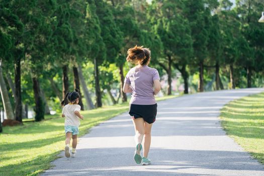 Mother and daughter runners are jogging in the park. Evening. Family activities . Mother and son in sportswear are running and having fun.