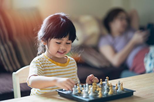 Little asian baby playing chess in the living room at home.Smart kid.fashion children. Little genius Child. Intelligent game.Chessboard. Baby activity concept.