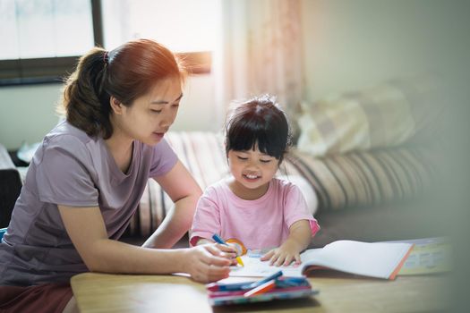 Cute little child painting with colorful paints. Asian girl and her mother using crayon drawing color.Baby artist activity lifestyle concept.