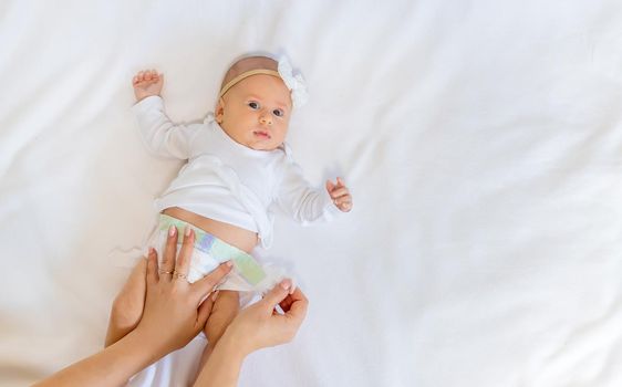 Mom is changing the baby's diaper. Selective focus. People.