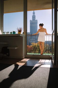 Back view of sexy lady in towel standing on balcony. Elegant woman at home.