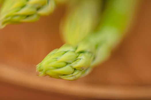 branches of fresh green asparagus on a wooden board, brown background, top view. Basic trend concept with copy space.